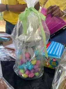 Clear gift bag filled with colorful candy eggs, tied with a green ribbon, resting on a table.
